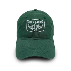 May include: A dark green baseball cap with a curved brim. The cap features a white embroidered patch with the words "SPACE RANGER" and a stylized emblem. The cap is made of a soft, durable fabric.