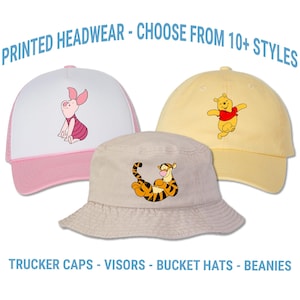 May include: Three hats with cartoon character designs. A pink and white trucker hat features Piglet. A yellow baseball cap has Winnie the Pooh. A beige bucket hat displays Tigger. Text reads "PRINTED HEADWEAR - CHOOSE FROM 10+ STYLES" and "TRUCKER CAPS - VISORS - BUCKET HATS - BEANIES".