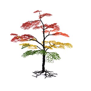 Pu&ograve; includere: Scultura di albero in filo metallico fatta a mano con tronco e radici neri. Il fogliame passa dal verde alla base al giallo e poi al rosso in cima, creando un'esposizione colorata. La scultura &egrave; ambientata su uno sfondo bianco.