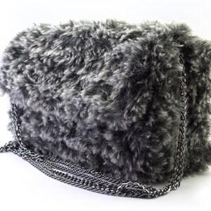 May include: A gray and white faux fur shoulder bag with a silver chain strap.