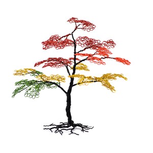 Pu&ograve; includere: Scultura di albero in filo metallico con tronco e radici neri. Le foglie variano dal verde al giallo al rosso, creando un'esposizione vibrante e colorata. L'albero &egrave; posto su uno sfondo bianco.