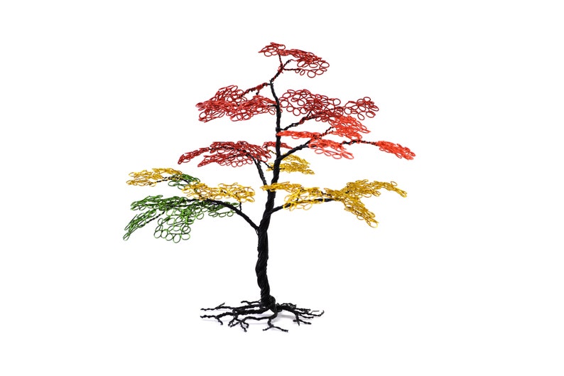 Pu&ograve; includere: Scultura di albero in filo metallico con tronco e radici neri. Le foglie variano dal verde al giallo al rosso, creando un'esposizione vibrante e colorata. L'albero &egrave; posto su uno sfondo bianco.