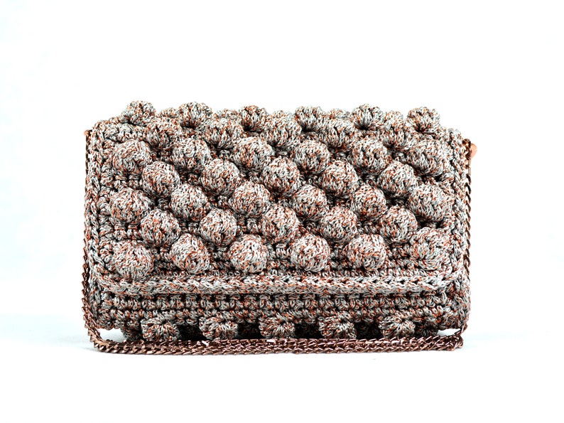 May include: A silver and copper crocheted clutch bag with a chain strap.