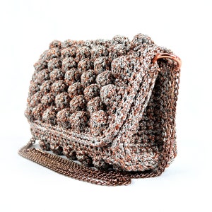May include: A crocheted handbag with a silver and brown color scheme. The bag has a chain strap and a textured, puffy design.