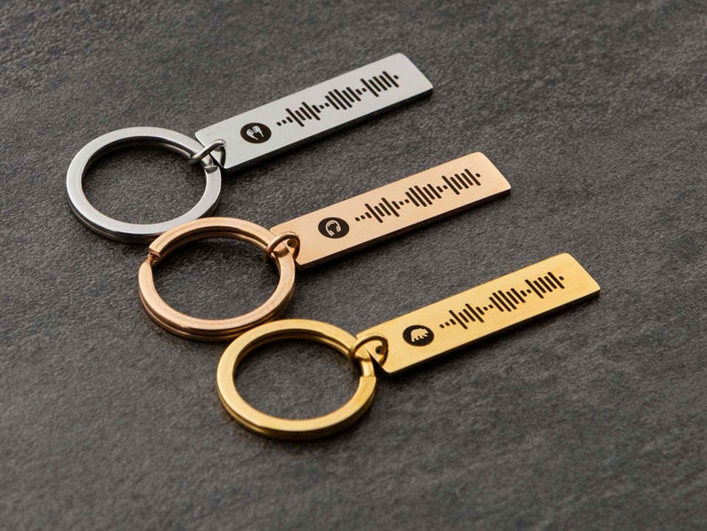 K&ouml;nnte beinhalten: Drei Schl&uuml;sselanh&auml;nger mit unterschiedlichfarbigen Metallringen und rechteckigen Anh&auml;ngern. Jeder Anh&auml;nger hat ein einzigartiges Schallwellendesign und ein kleines Symbol.