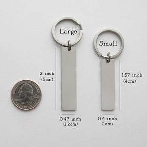 K&ouml;nnte beinhalten: Zwei silberne Schl&uuml;sselanh&auml;nger mit rechteckigen Anh&auml;ngern. Der gr&ouml;&szlig;ere Schl&uuml;sselanh&auml;nger ist 5 cm lang und 1,2 cm breit. Der kleinere Schl&uuml;sselanh&auml;nger ist 4 cm lang und 1 cm breit. Die Schl&uuml;sselanh&auml;nger sind mit "Large" und "Small" beschriftet.