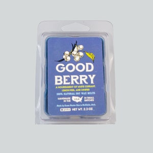 May include: A blue and white label with the text "GOOD BERRY" and a drawing of white berries. The label reads "A nourishment of white currant, lemon peel, and juniper. 100% natural soy wax melts. Handmade in the USA. In small batches. Net Wt. 2.3 oz."