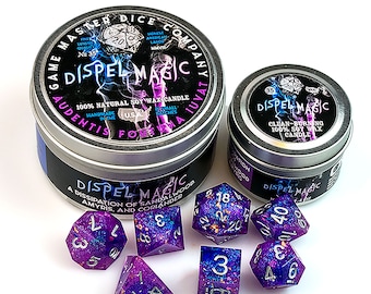 May include: Two silver tins with black labels that read "Dispel Magic" and "Audentis Forna Juvat". The labels also include the text "100% Natural Soy Wax Candle" and "Handmade in the USA".  The tins are surrounded by seven purple and blue dice with gold and silver glitter.
