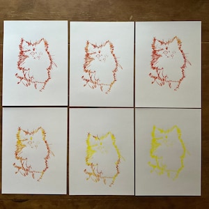 Puede incluir: Seis tarjetas blancas con dibujos de línea rojos y amarillos de un gato en cada tarjeta. El gato está dibujado de forma estilizada con un aspecto esponjoso. Las tarjetas están dispuestas en dos filas de tres.