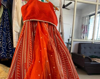 May include: An orange and gold embroidered dress with a matching top. The dress has a sheer overlay with a scalloped hemline.