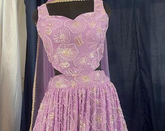 May include: A lavender-colored, two-piece formal outfit with floral embroidery and gold accents. The top has a sweetheart neckline and the skirt is pleated. A matching sheer scarf with gold trim completes the ensemble.