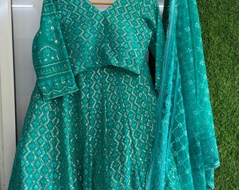 Könnte beinhalten: Ein türkisfarbenes, besticktes Kleid mit passendem Dupatta. Das Kleid hat einen V-Ausschnitt und Dreiviertelärmel. Der Dupatta ist durchsichtig und hat ein zartes Muster.