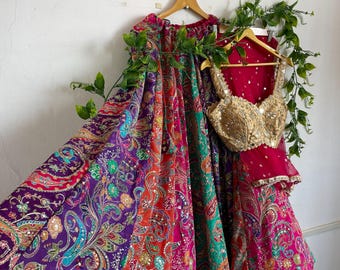 May include: A multi-colored lehenga skirt featuring a vibrant paisley pattern in shades of purple, orange, and green, paired with a sleeveless gold-toned blouse heavily embellished with sequins and embroidery, and a sheer magenta dupatta.