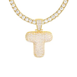 May include: A gold chain necklace with a large, cubic zirconia encrusted letter T pendant.