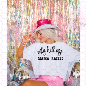 May include: A white t-shirt with the text "only hell my mama raised" in black lettering. The shirt is being worn by a person wearing a pink cowboy hat and a pink skirt. The background is a pink and white iridescent foil curtain.