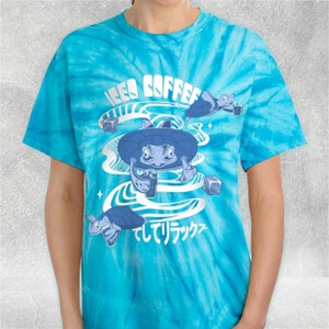 Può includere: T-shirt turchese tie-dye con un design a cartoni animati. Il design include le parole "ICED COFFEE" in bianco, tartarughe blu con caffè freddo, cubetti di ghiaccio e testo giapponese.