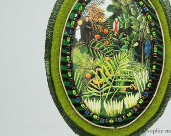 Broche bordado a mano en tela de fieltro y cuero con cuentas miyuki, alrededor de una trenza dorada, en homenaje a la obra de Le Douanier Rousseau, Paisaje exótico.