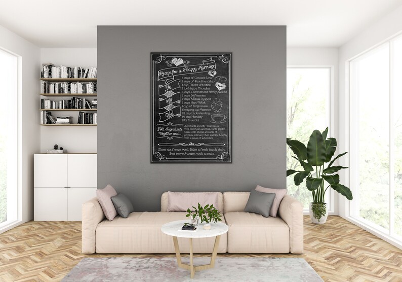 May include: A black chalkboard with white chalk writing that reads "Recipe for a Happy Marriage". The recipe lists ingredients such as "1 cup of Genuine Love", "1 cup of Tender Affection", "1 cup of Forgiveness", "1 cup of Mutual Respect", and "1 cup of Understanding". The chalkboard is hanging on a gray wall in a living room setting.