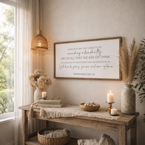 May include: A rectangular wall sign with a wooden frame featuring the black printed text: Now unto him that is able to do exceeding abundantly above all that we ask or think, according to the power that worketh in us. Unto him be glory, forever and ever. Amen. Ephesians 3:20-21.