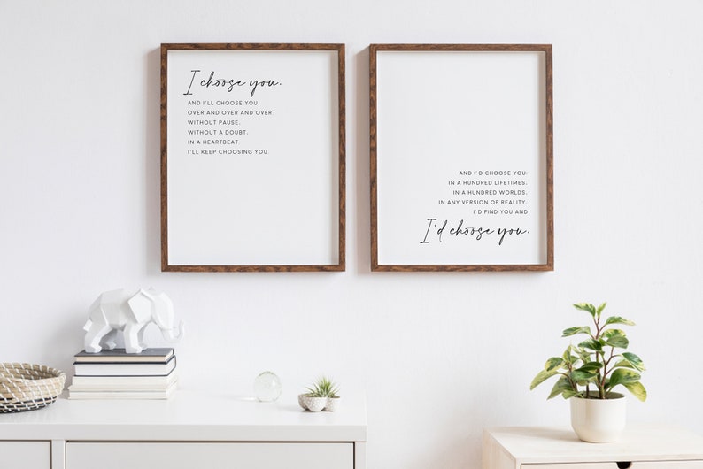 Pu&ograve; includere: Due stampe da parete rettangolari con cornici in legno marrone scuro. La stampa a sinistra riporta il testo I choose you. And I'll choose you. Over and over and over without pause. Without a doubt. In a heartbeat. I'll keep choosing you. La stampa a destra riporta il testo And I'd choose you in a hundred lifetimes. In a hundred worlds. In any version of reality. I'd find you and I'd choose you.