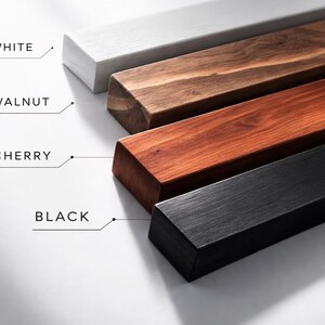 May include: Four wooden bars in white, walnut, cherry, and black, with text labels. The bars have beveled edges. The walnut and cherry bars show the wood grain. Measurements are not included.