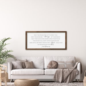 May include: A framed wood sign with a white background and black text. The text reads: "May the road rise up to meet you. May the wind be always at your back. May the sun shine warm upon your face. The rains fall soft upon your fields. And until we meet again, may God hold you in the palm of his hand." The text is signed "Irish Blessings".