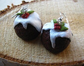 May include: A pair of dangle earrings featuring miniature Christmas pudding ornaments with white icing and green holly accents.