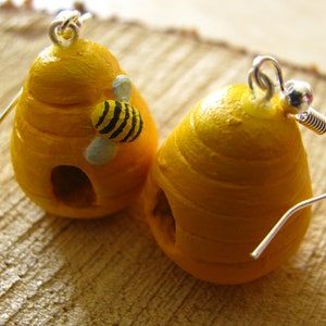 May include: A pair of yellow beehive earrings with a small bee charm on one earring. The earrings are made of polymer clay and have a silver hook.