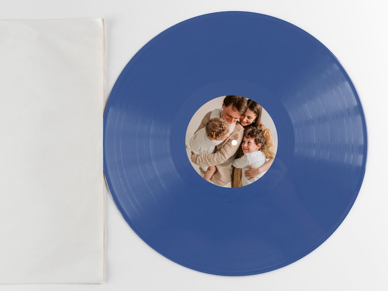 May include: A blue vinyl record with a photo of a family of four. The photo shows a man, a woman, and two children. The man is holding the younger child, and the woman is holding the older child. The photo is in a circular frame in the center of the record.