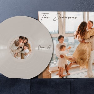 May include: A white vinyl record with a photo of a family of four on the label. The label says "Side A". The record is next to a brown cardboard record sleeve with a photo of a family of four on the front. The sleeve has the text "The Johnsons" written in cursive.