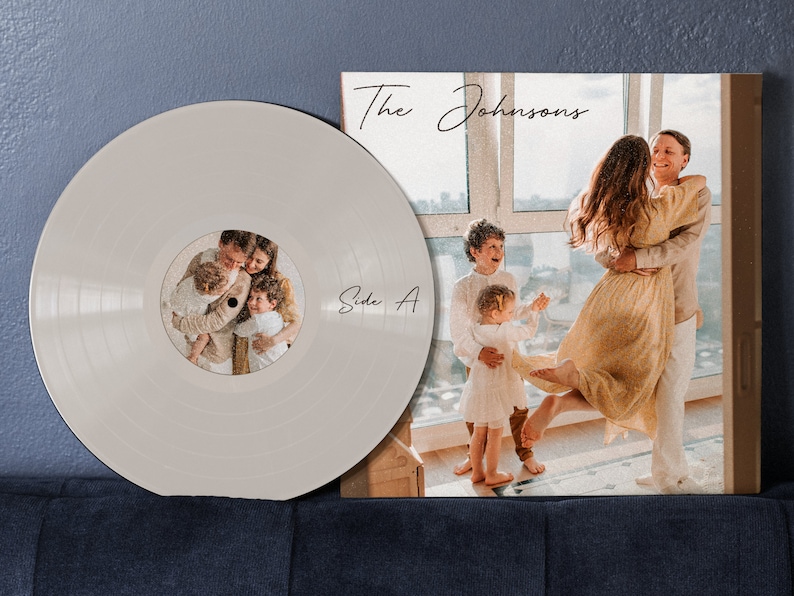 May include: A white vinyl record with a photo of a family of four on the label. The label says "Side A". The record is next to a brown cardboard record sleeve with a photo of a family of four on the front. The sleeve has the text "The Johnsons" written in cursive.
