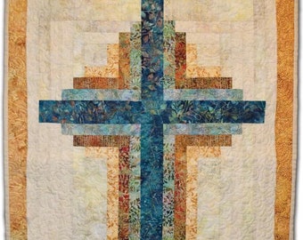 May include: A quilt with a blue and brown cross design. The cross is made up of multiple layers of fabric, creating a layered effect. The background of the quilt is white with a subtle pattern.