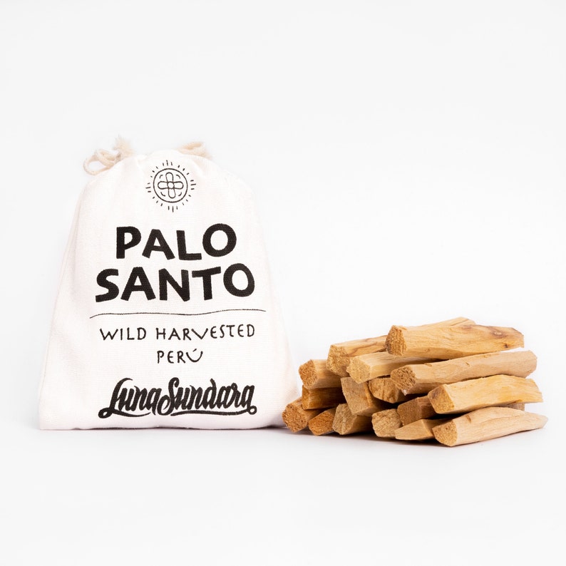 以下が含まれることがあります： 「PALO SANTO」の黒い文字と「WILD HARVESTED PERU」とLuna Sundaraのロゴがプリントされた白いキャンバスバッグ。右側には、薄茶色のパロサントの棒が積み重ねられています。
