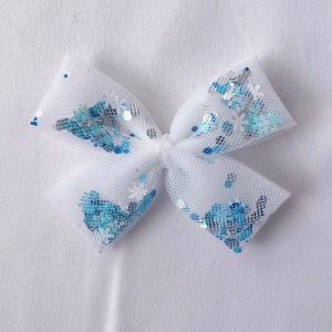 May include: A white tulle bow with blue and silver glitter accents.