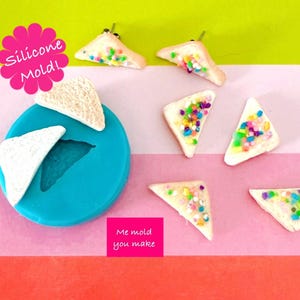 May include: A turquoise silicone mould in the shape of triangular bread, with several miniature bread slices decorated with colourful sprinkles. The image also includes text that reads "Silicone Mold!" and "Me mold you make."