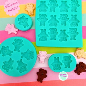 May include: A collection of teal silicone moulds featuring bear-shaped cavities in square, circular, and oval formats. The set includes small bear-shaped figures in tan, pink, and brown colours. Text on the image reads Silicone Molds! and ME MOLD YOU MAKE.