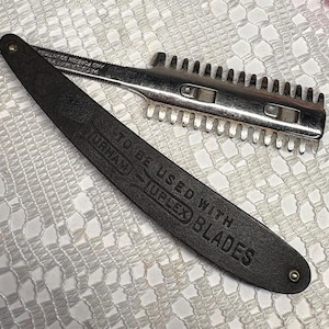 Może przedstawiać: Zabytkowa brzytwa z srebrnym ostrzem i czarną rączką. Na rączce znajduje się napis "TO BE USED WITH UPLEX BLADES". Brzytwa jest przeznaczona do golenia i pielęgnacji.