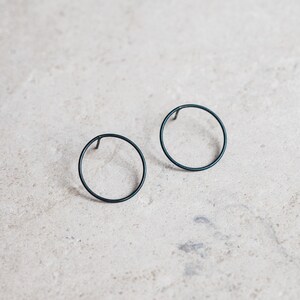 Pendientes delicados de plata con forma geométrica circular, aros sencillos y minimalistas.