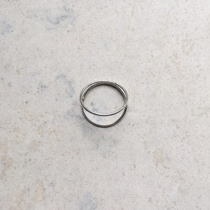 May include: A silver ring with a double band design. The ring is simple and elegant.