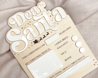 May include: A wooden sign with the words "Dear Santa" in white letters. The sign has spaces for a child to fill in their age, whether they have been naughty or nice, and their Christmas wish.