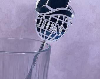 May include: A silver cocktail stirrer with a black cowboy hat and a globe with the word "NEW" on it.