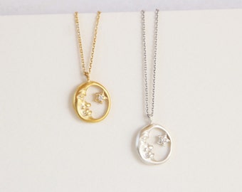 Puede incluir: Dos collares con colgantes celestiales. Uno es dorado, con una luna creciente y una estrella. El otro es plateado, con un diseño similar. Ambos colgantes están en cadenas delicadas, ideales para el uso diario.