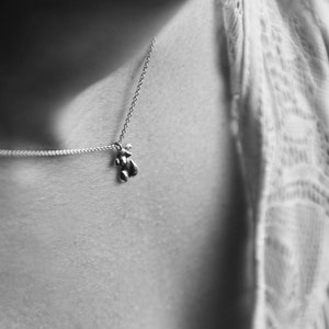 Peut inclure: Un collier en cha&icirc;ne argent avec un petit pendentif en forme d'ours.