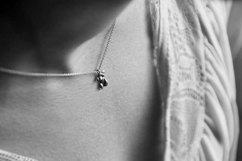 Peut inclure: Un collier en cha&icirc;ne argent avec un petit pendentif en forme d'ours.