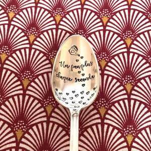 Peut inclure: Une cuillère en argent gravée des mots "Un peu plus chaque seconde". La cuillère est décorée de petits cœurs et d'un arrosoir.