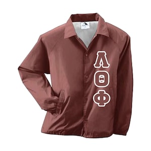 May include: A maroon coach jacket with a button-up front, collar, and side pockets. White Greek letters are vertically aligned on the front. The jacket is made of a lightweight material.