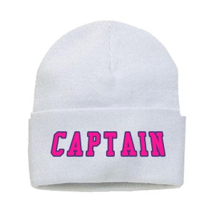 May include: White beanie hat with the word "CAPTAIN" in bright pink letters with a dark blue outline. The hat is a classic, folded-brim style, perfect for cold weather.