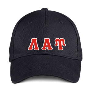 May include: A navy blue baseball cap featuring the letters "AAT" in red with a white border. The cap has a curved peak and a button on the crown. The letters are in a bold, collegiate style.