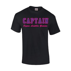 May include: Black t-shirt with the text "CAPTAIN" in pink with a purple outline and the text "Sigma Lambda Gamma" in pink below.