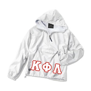 May include: White hooded anorak jacket with a front pocket and a half-zip closure. The jacket features the Greek letters KΦΛ in red block letters on the lower front. The jacket has a drawstring at the bottom hem and a small tag on the lower left.